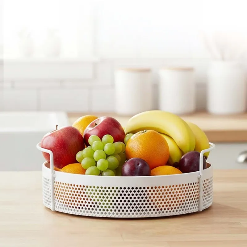 White round perforated metal basket filled with fruit