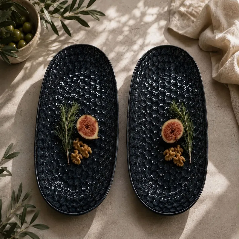 Two dark blue textured oval platters styled with figs, rosemary and walnuts