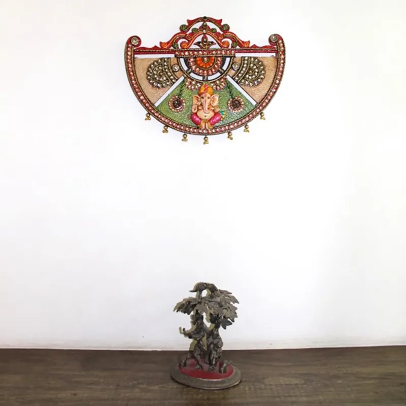 Ganesha wall accent mounted on a plain wall above a tabletop