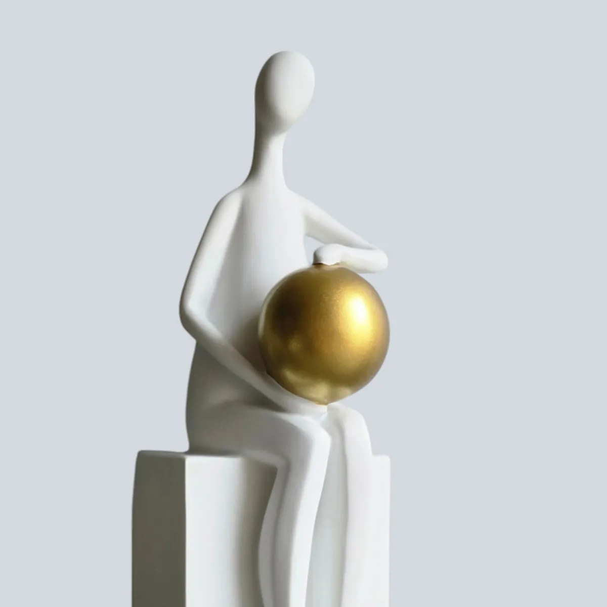 Close-up of a white abstract figurine and its gold sphere