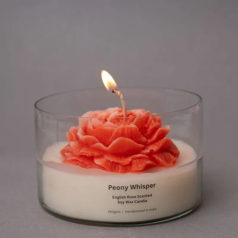 Lit rose-shaped candle in a clear glass container with a visible flame