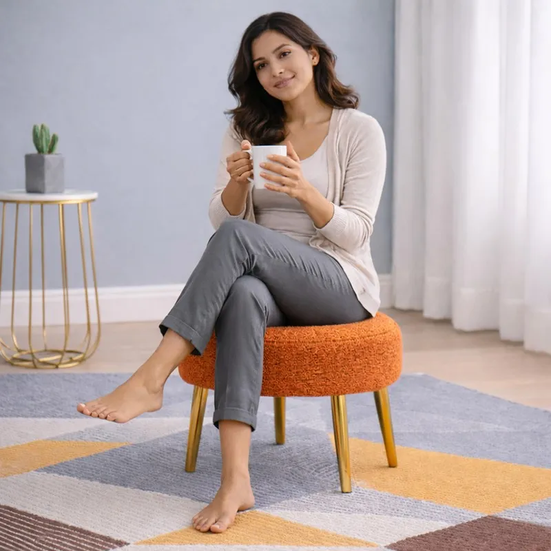 Person seated on an orange bouclé stool with gold legs