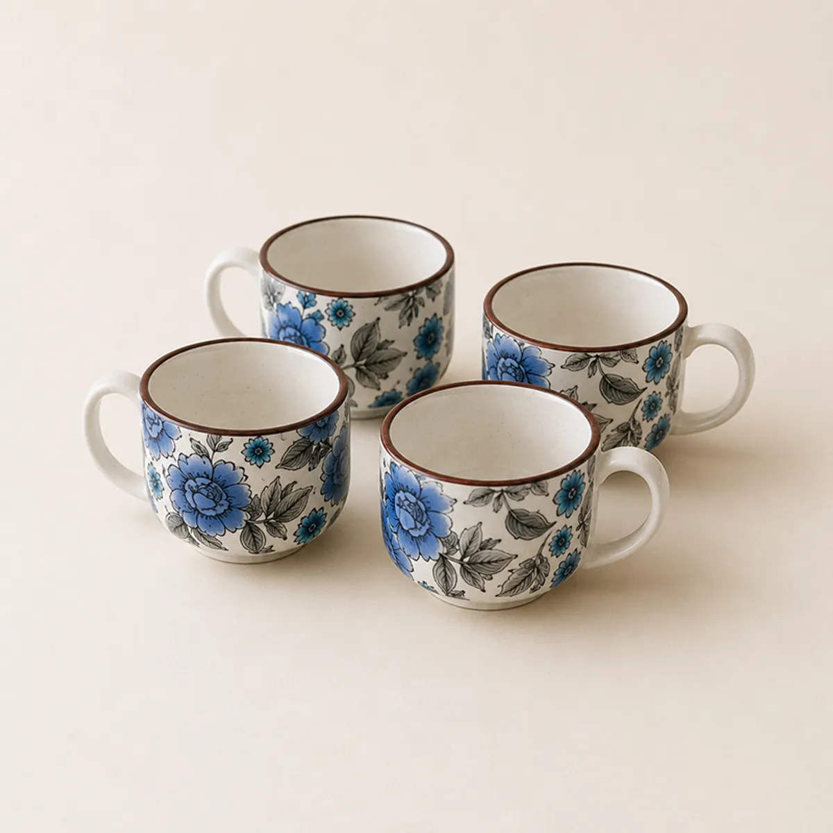 Four blue and white floral ceramic tea cups arranged together